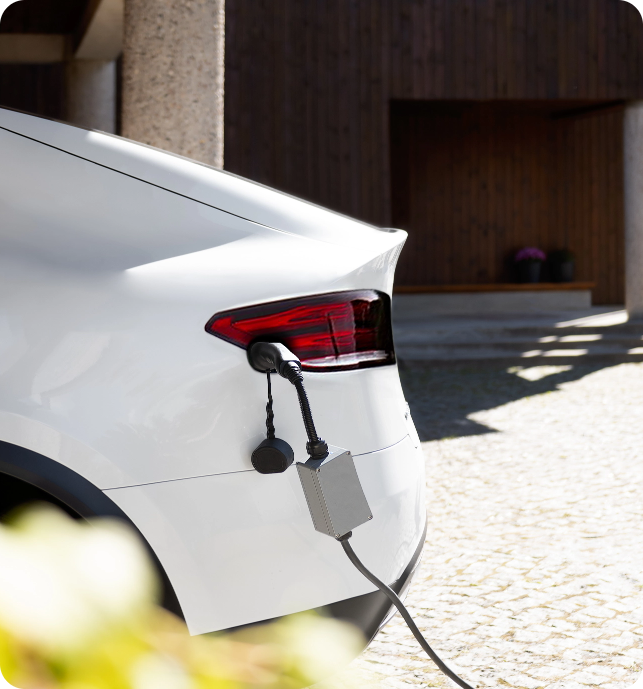 A sleek and modern CITA Home EV Charger mounted on a home garage wall, charging a Tesla, showcasing compatibility with all EV models.
